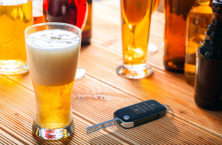 Car key and beer glass on a wooden pub counter.